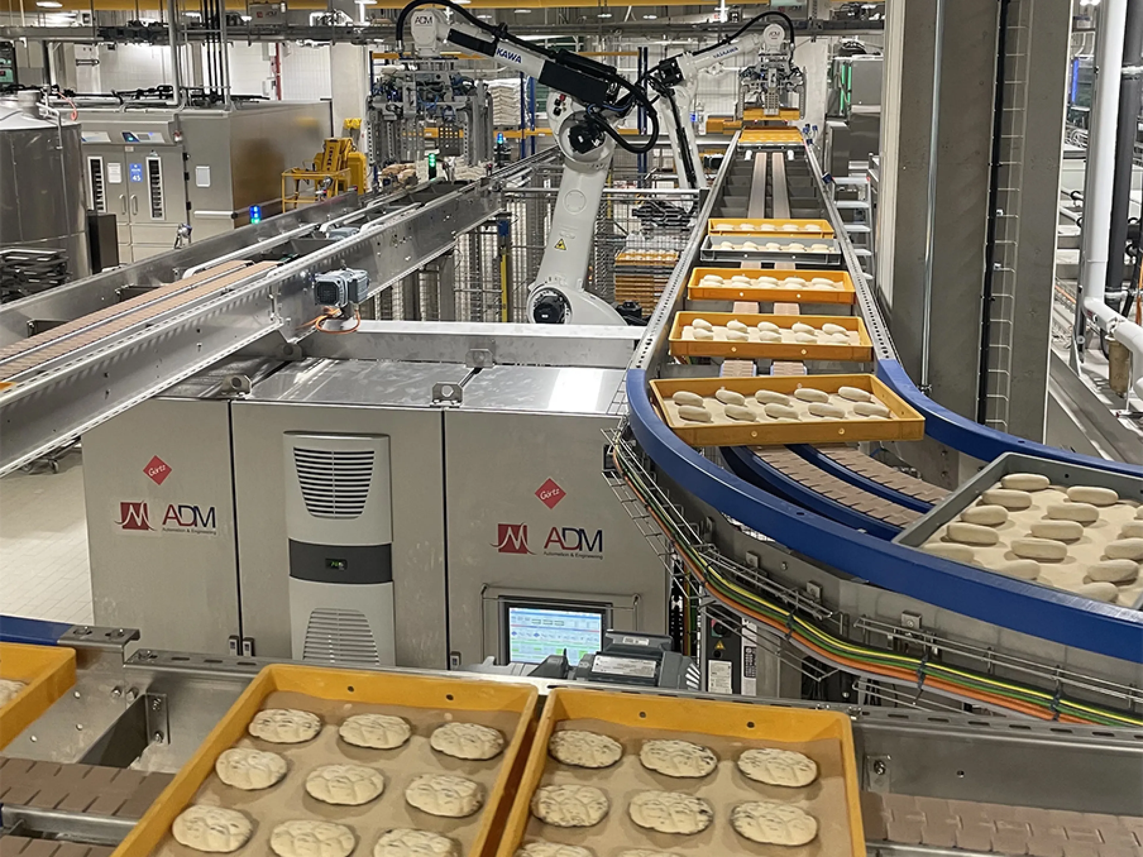 Two of the four Motoman GP180 robots remove the planks from the freezer outlet and place them on a conveyor belt, Photo: Yaskawa Two of the four Yaskawa Motoman GP180 robots remove the planks from the freezer outlet and place them on a conveyor belt
